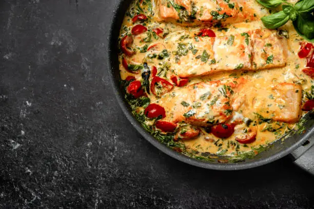 Photo of Close up of delicious tuscan cream salmon with spinach in a pan
