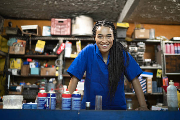 portrait of a female mechanic standing behind de counter in a auto repair shop - car equipment smiling working imagens e fotografias de stock