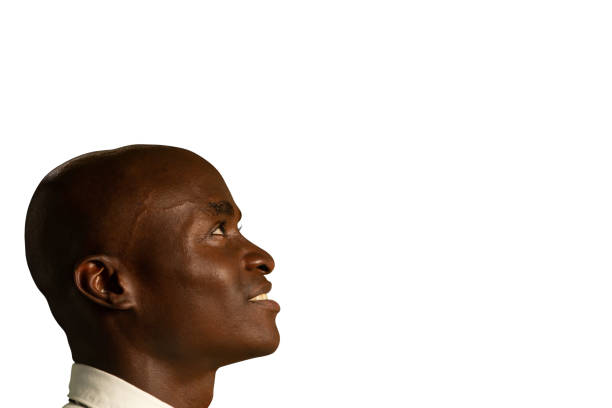 Side view close up of a bald young African American businessman wearing a shirt and tie, looking up and smiling