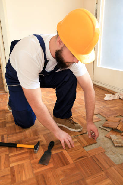 istock Construction worker and constructor is working on renovation of apartment. Handyman is removing old wooden parquet flooring using yellow hammer and scraping tool. Builder dismantles parquet floor. 1175896779