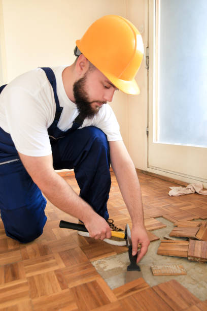 istock Construction worker and constructor is working on renovation of apartment. Handyman is removing old wooden parquet flooring using yellow hammer and scraping tool. Builder dismantles parquet floor. 1175896823