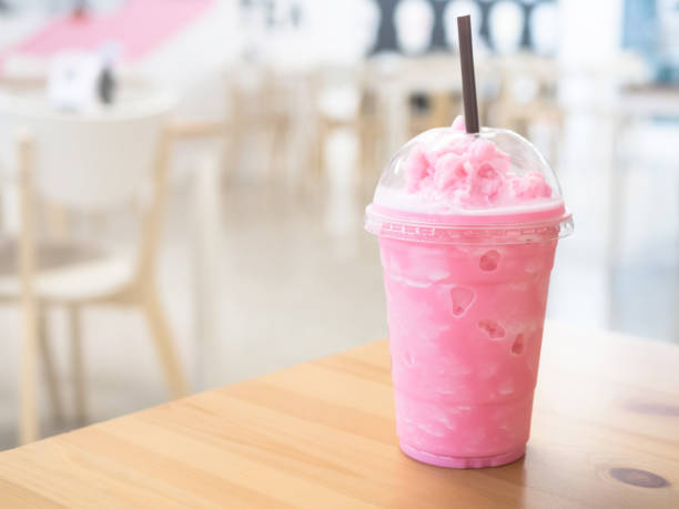 istock Cold milk smoothie in a plastic cup on a wooden table and has sunlight a beautiful background. 1175897220