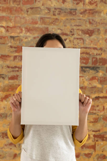 istock Blank canvas held in front of brick wall 1175898244