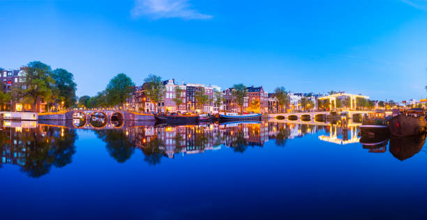 Panoramic View of the Magere Brug Bridge and Canal Side Houses on the Amstel River at Twilight, Amsterdam, Netherlands stock photo