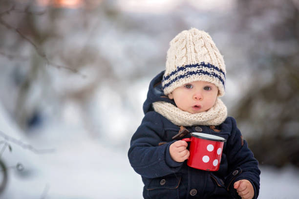 fratelli dolci, bambini che hanno una festa invernale nella foresta innevata.  giovani fratelli, ragazzi, che bevono tè dal thermos. bevande calde e bevande con il freddo - cold discussion outdoors snow foto e immagini stock