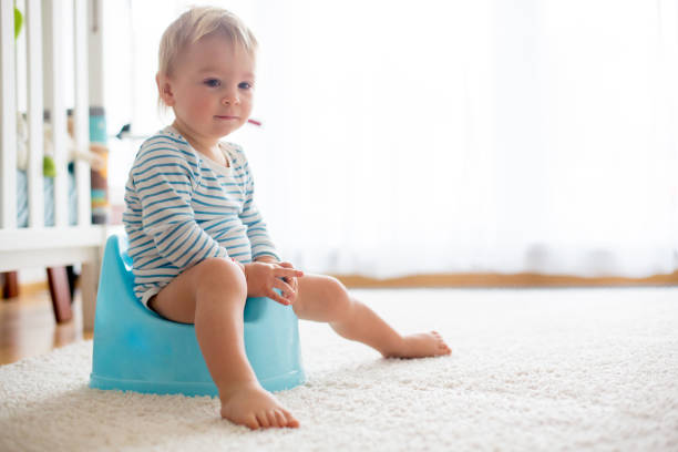 Cute toddler boy, potty training, playing with his teddy bear Cute toddler boy, potty training, playing with his teddy bear on potty potty toilet child bathroom stock pictures, royalty-free photos & images