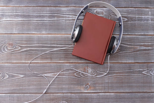 istock Headphones and old book over wooden table. 1175909729
