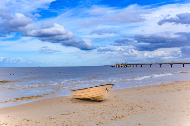 barca solitaria sdraiata sulla spiaggia di sabbia sulla costa dell'isola usedom, germania. - rowboat nautical vessel usedom sand foto e immagini stock