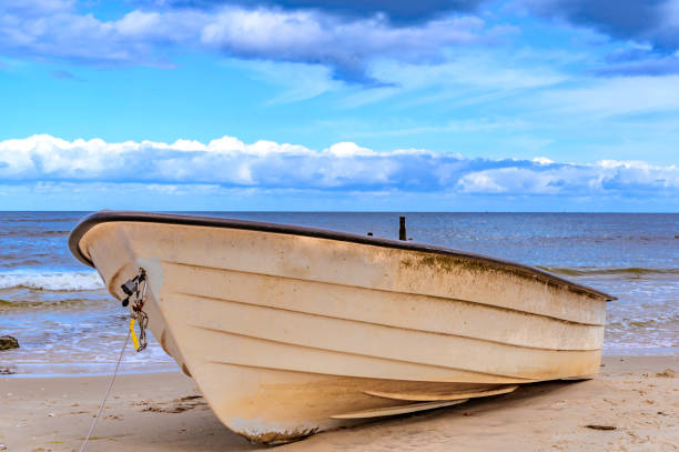 barca solitaria sdraiata sulla spiaggia di sabbia sulla costa dell'isola usedom, germania. - rowboat nautical vessel usedom sand foto e immagini stock