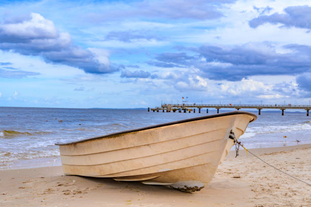 barca solitaria sdraiata sulla spiaggia di sabbia sulla costa dell'isola usedom, germania. - rowboat nautical vessel usedom sand foto e immagini stock