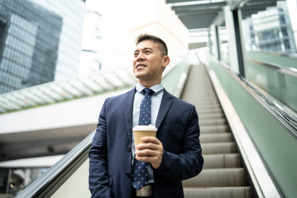 istock Smiling businessman moving down on escalator at workplace 1175911486