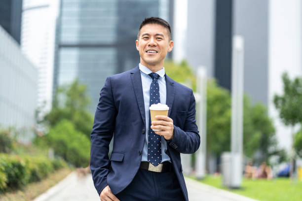 istock Businessman holding coffee cup and documents on street 1175911502