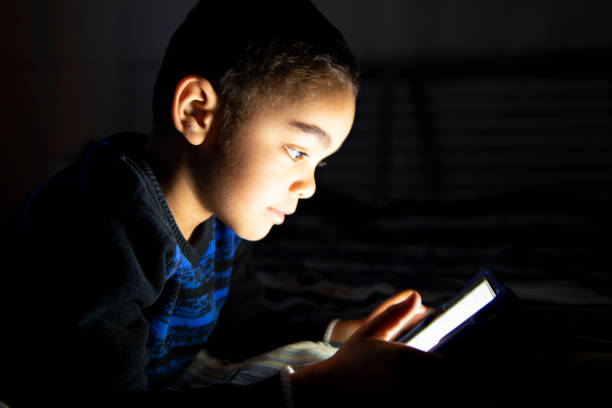 istock Little boy, lay in a dark, playing with tablet on the bed 1175911536