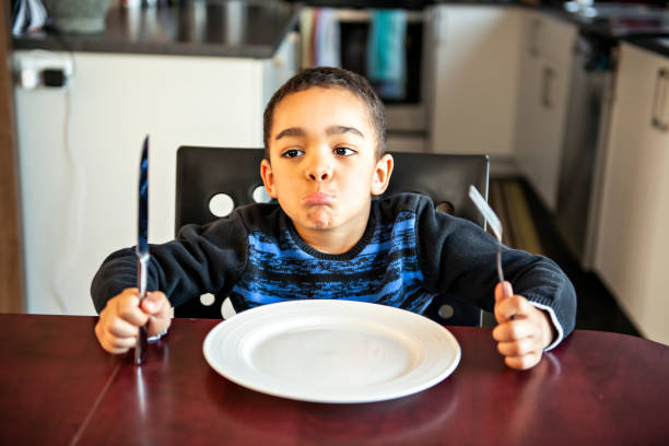 menino que senta-se na tabela da cozinha com placa vazia - healthy eating snack child domestic kitchen - fotografias e filmes do acervo