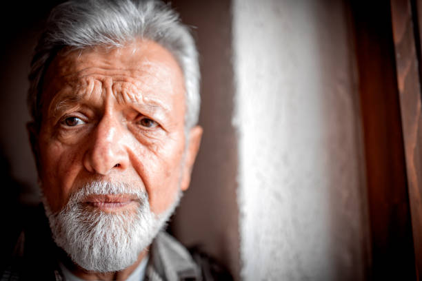 Sad Mature man Suffering From Agoraphobia Looking Out Of Window