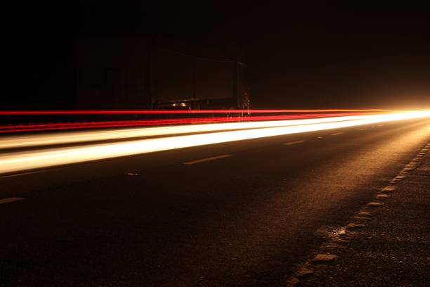 imagem da técnica da fotografia do efeito do lightstream, retrato da exposição longa das luzes da cabeça e da cauda dos carros que viajam em uma pista dupla na noite - long exposure flash - fotografias e filmes do acervo