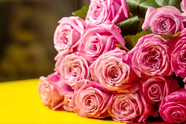 istock pink roses on yellow table, background 1175918741