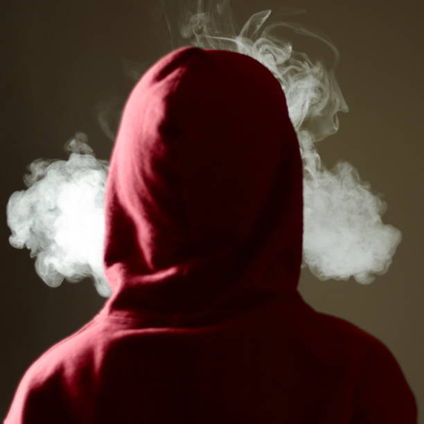 giovane maschio in felpa con cappuccio rosso che svapa fumando, espira vapore spesso, vista posteriore isolata - pipe organ foto e immagini stock