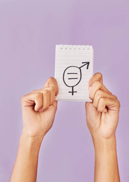Studio shot of an unrecognizable woman's hands holding up a placard with gender symbols on it