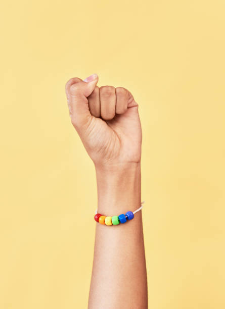 The power belongs to us Studio shot of an unrecognizable woman raising a fist while wearing a rainbow bracelet bi black stock pictures, royalty-free photos & images