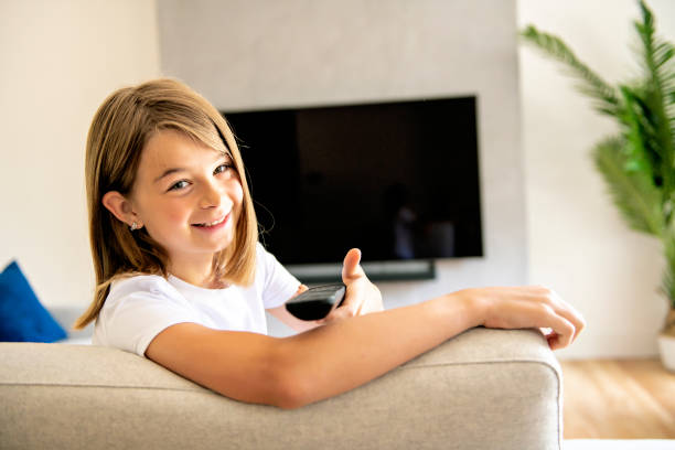 istock A girl holding remote control and watching TV show 1175920956