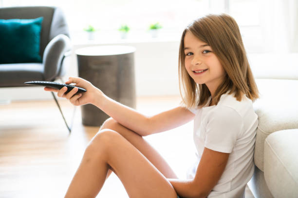 istock A girl holding remote control and watching TV show 1175921047