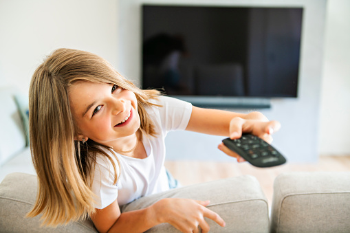 Girl holding remote control and watching TV show