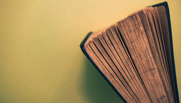istock Close up Beautiful open old book top view on a yellow background table. 1175922733