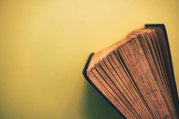 istock Close up Beautiful open old book top view on a yellow background table. 1175923271