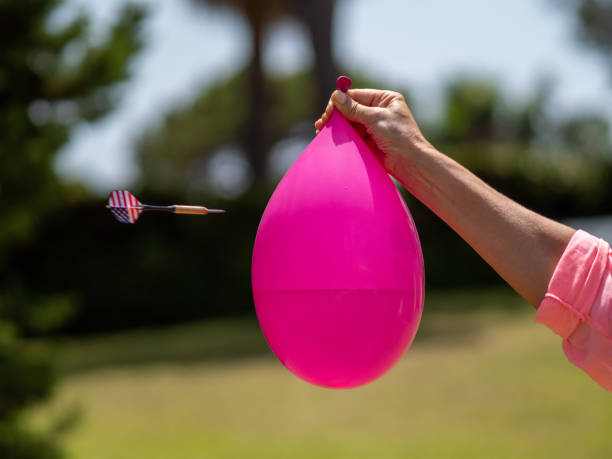 sequence in several photos of the launch of a dart against a water-filled balloon and its subsequent explosion. - rubber dart imagens e fotografias de stock