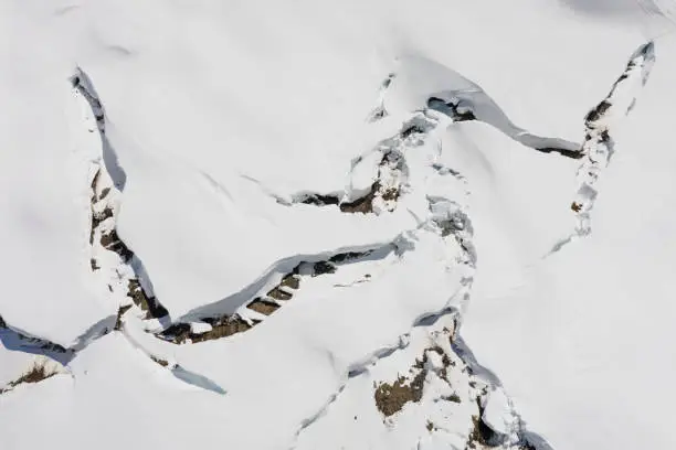 arial view of snow glide crack in mountains showing danger of avalanches
