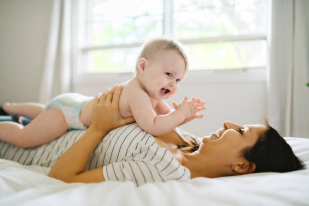 istock Mother and child on a white bed playing in sunny bedroom 1175925077