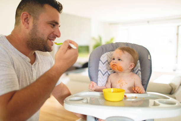istock A Little baby eating her dinner and making a mess with dad on the side 1175925243