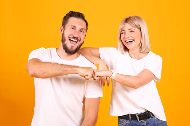 Young people of opposite sex and hair color on yellow background. stock photo