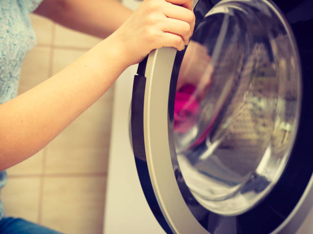 istock Person putting clothes into washing machine 1175928643