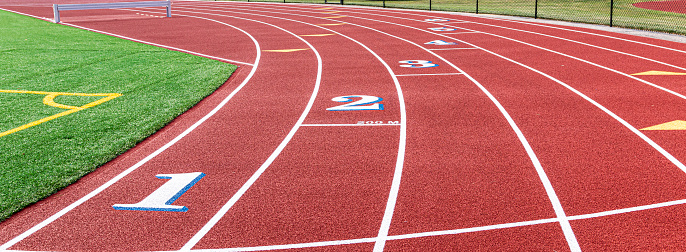 Landscape view of a red track with white numbers that have blue trim at the two hundred meter start.
