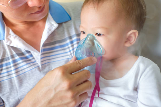 istock Sick little kid with respiratory problem with oxygen mask breathes through nebulizer at doctor clinic 1175934238