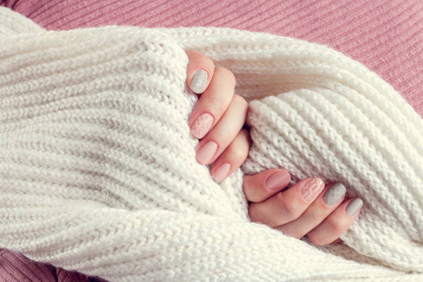 knitted texture manicure on nails from pink and gray colors with white scarf