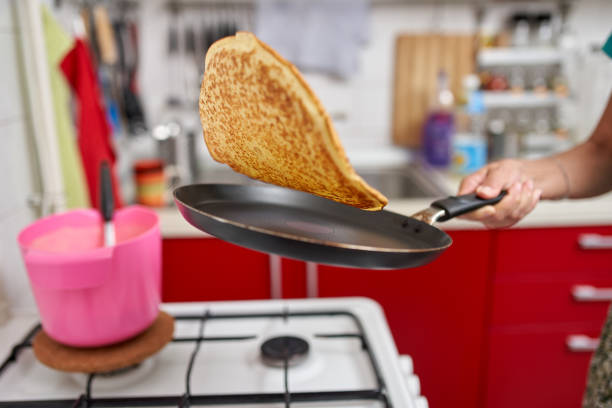 donna flipping pancake in padella - lanciare foto e immagini stock