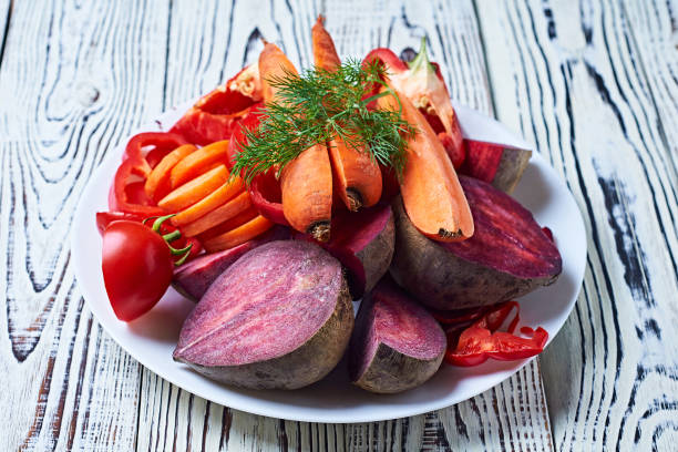 istock Heap of different fresh ripe vegetables on circle ceramic plate lies on old white rustic wooden table on kitchen. Healthy food concept 1175944541