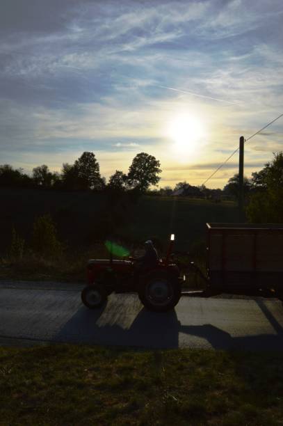 istock a small tractor on the road and sunset 1175950309