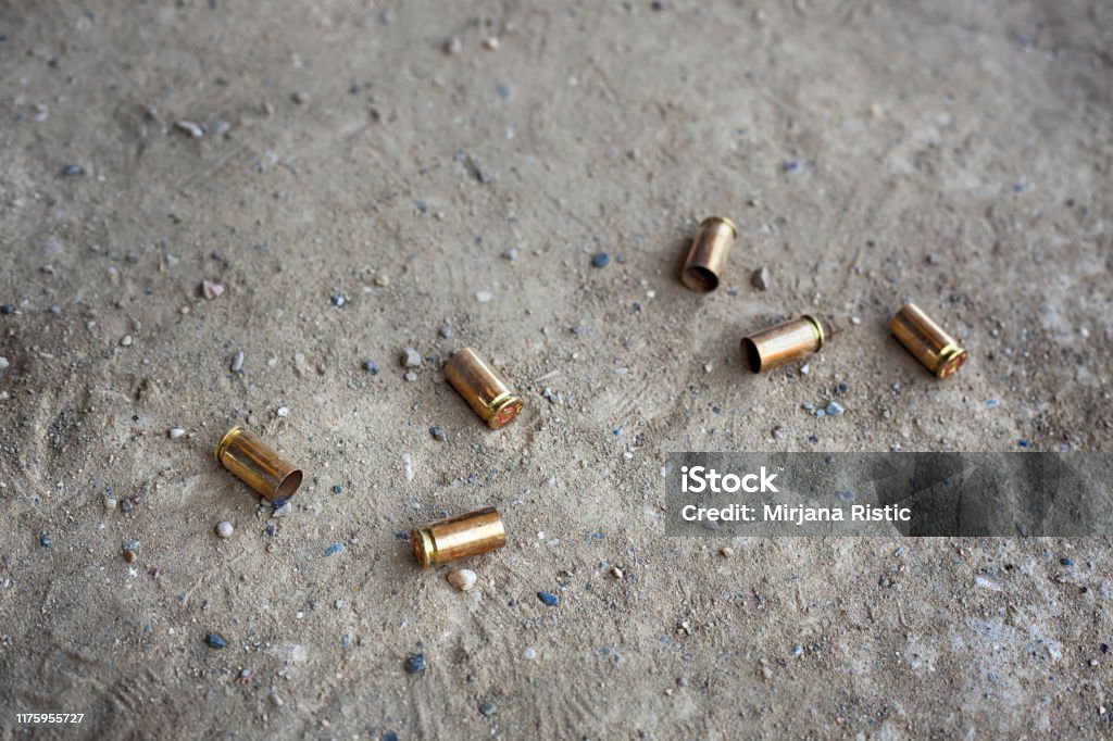 9 mm bullet shells lying on the ground 9 mm empty bullet shells lying on desert dirt with some rocks Blank Stock Photo