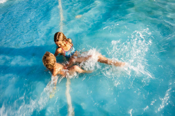 istock Boy and girl playing in swimming pool 1175959331
