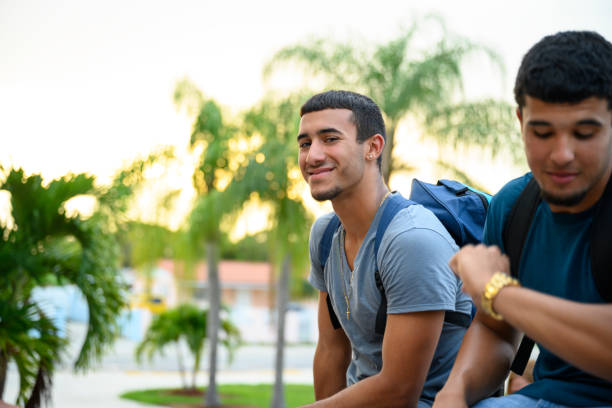 fiducioso liceale ispanico seduto fuori con un amico - high schooler foto e immagini stock