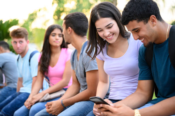 istock Hispanic high-schoolers sitting outdoors on campus wall 1175962797