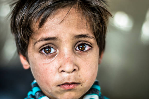 крупным планом бедных глядя голодный мальчик-сирота в лагере беженцев с печальным выражением на лице и его лицо и одежда грязные и глаза по� - hungry child human hand india стоковые фото и изображения