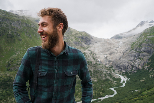 Portrait of young Caucasian  man smiling on the background of glacier in Swiss Alps