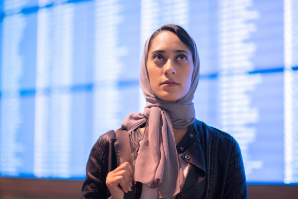 istock Muslim woman checking flight information at airport 1175998320