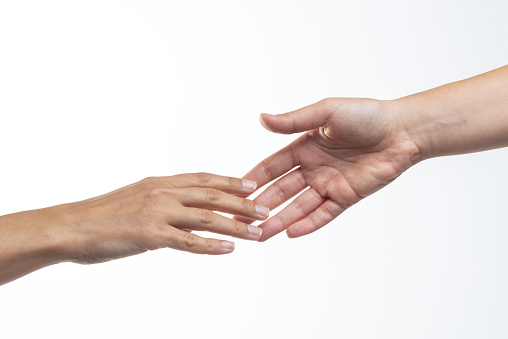 Two hands are almost touching for handshake on white background.