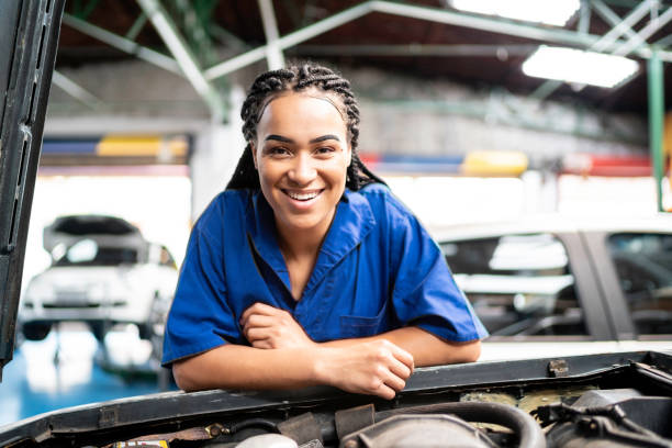 portrait of a female mechanic working on a auto repair shop - auto repair shop adult auto mechanic blue imagens e fotografias de stock